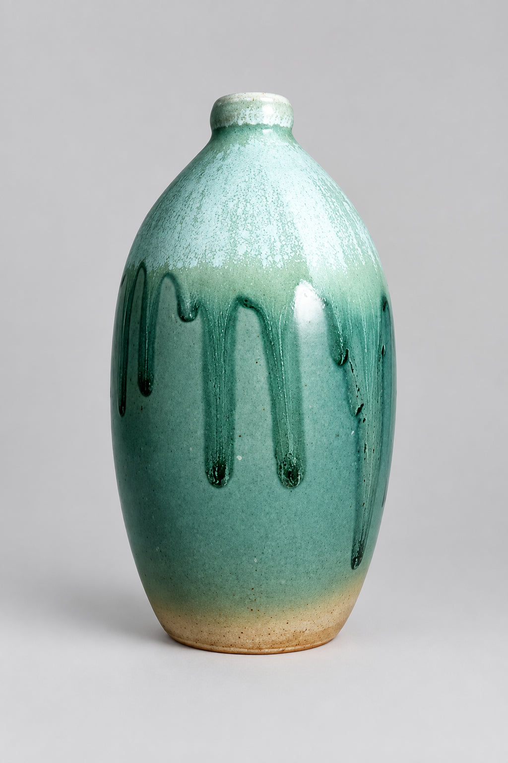 A ceramic bottle vase with a rounded body, short neck, and a matte glaze that transitions from teal-green at the top to a warm beige at the base, featuring dark green drip patterns on the front.
